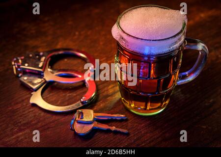 Chope de bière mousseuse avec des menottes et clés symbolisant l'alcool au volant l'arrestation Banque D'Images