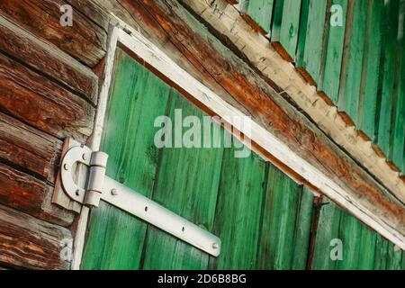 Charnières en fer blanc peint sur les portes en bois vert du hangar de près. Arrière-plan texturé et détaillé avec planches de bois peintes de peinture verte avec espace de copie Banque D'Images