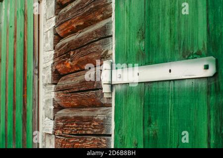 Charnières en fer blanc peint sur les portes en bois vert du hangar de près. Le fond texturé et détaillé avec des planches de bois de grange est peint de la douleur vert vif Banque D'Images
