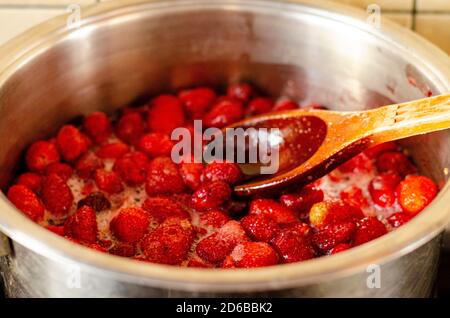 Les fraises sont bouillies avec du sucre dans la casserole. Banque D'Images