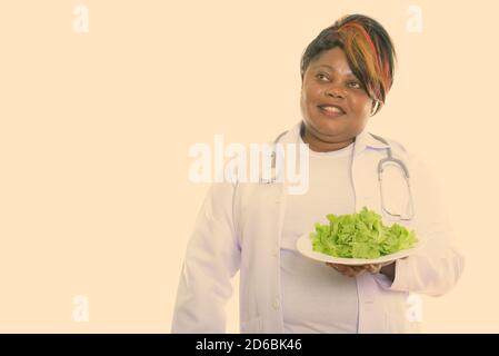 Un médecin de femme africaine noire, content et attentif, souriant tout en tenant la laitue servie sur la plaque blanche Banque D'Images