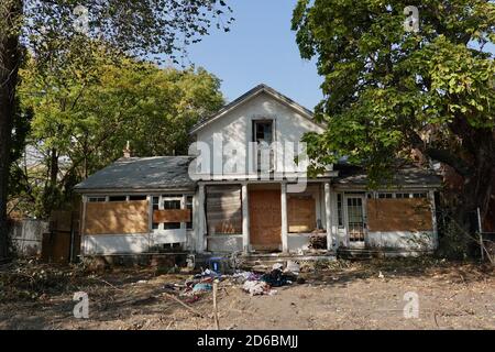 Une maison abandonnée arraisonnée avec des déchets tout autour. Banque D'Images