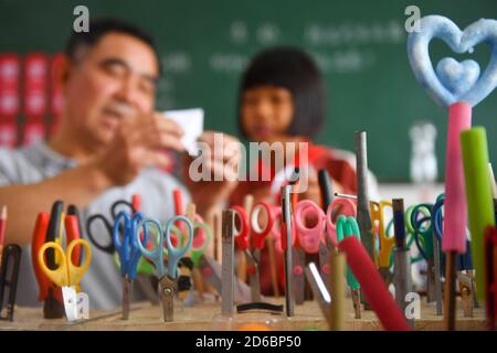 (201016) -- LUXI, le 16 octobre 2020 (Xinhua) -- Li Xuezhan (L) et un étudiant font des travaux scientifiques à l'école du comté de Luxi, dans la province de Jiangxi, en Chine orientale, le 14 octobre 2020. Chaque fois que Li Xuezhan entre dans l'école centrale de la ville de Xuanfeng dans le comté de Luxi avec sa valise remplie d'aides pédagogiques faites à la main, il sera suivi et entouré par des étudiants. Li, 58 ans, est devenu professeur de sciences en 1996. En raison du manque d'aides pédagogiques, il a dû recueillir des bouteilles vides, du bois, des pneus cassés et les transformer en aides pédagogiques pour la classe scientifique. Maintenant que les conditions d'enseignement de l'école hav Banque D'Images