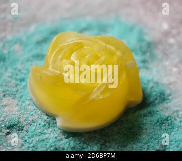 Petit savon jaune naturel fait à la main sous forme de rose sur fond parfumé de sel de mer. Banque D'Images