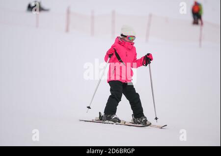 bonne petite fille active en costume de ski rose pendant l'hiver ski sur la neige blanche montagne alpin station de loisirs Banque D'Images