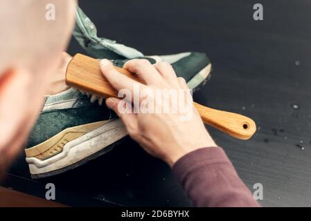 Chaussures de nettoyage en daim. Un travailleur dans un atelier de chaussures nettoie une pile de chaussures. Banque D'Images