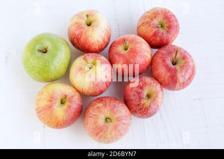 Vue de dessus de plusieurs pommes rouges et une pomme verte sur une ancienne table en bois blanc Banque D'Images