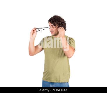 Confusion jeune homme fixant des lunettes, essayant de regarder à travers les lentilles, mauvaise vision de la myopie. Problème oculaire masculin, souffrant de fatigue oculaire, de mal et Banque D'Images