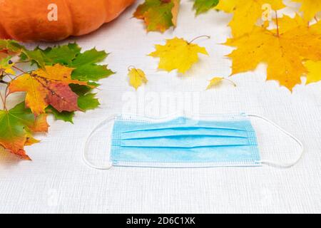 Feuilles d'érable, masque médical, citrouille sur fond blanc. Concept, automne, vitamines, protection contre le coronavirus. Photo de haute qualité Banque D'Images