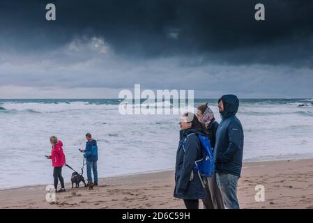 Une famille de vacanciers se tenant sur une plage de Fistral venteuse et profitant de la vue sur la baie de Fistral à Newquay, dans les Cornouailles. Banque D'Images