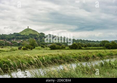 Glastonbury Tor au loin dominant le canton de Glastonbury. Un petit flux local traverse le premier plan. Personne. Copier l'espace. Banque D'Images