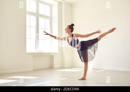 Fille debout avec la jambe étirée et pratiquant le ballet classique ou danse moderne en studio Banque D'Images