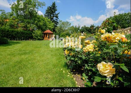 Beau jardin de fleurs de roses et un petit gazebo Banque D'Images