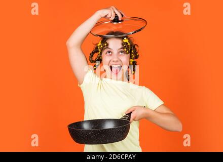 bonne enfance. gaie enfant avec des pillards. ménage de l'enfance. petite femme tient la poêle. cuisine dans la cuisine. concept de ménage. cuisine pour enfants à la maison. Banque D'Images