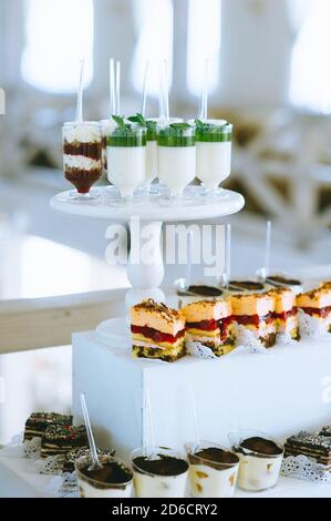 Bar à bonbons pour mariages avec petits gâteaux aux couleurs vives différentes, macarons, gâteaux, gelée et fruits. Banque D'Images