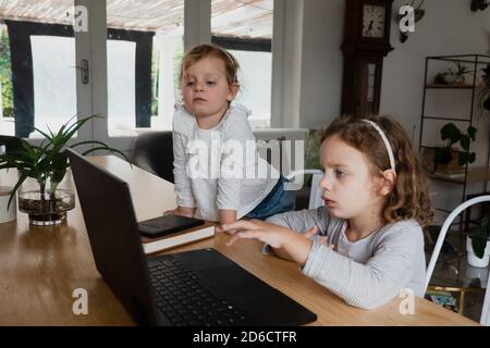 Deux sœurs de sexe féminin regardant des leçons en ligne sur ordinateur portable en train de concerter tout en apprenant. Banque D'Images