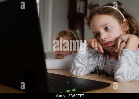 Deux jeunes enfants regardent l'école en ligne sur un ordinateur portable Banque D'Images