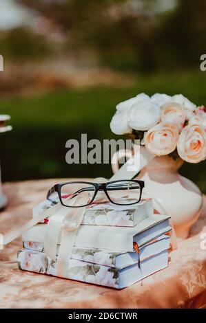 Gros plan de lunettes sur des carnets vintage sur une table près d'un vase avec des fleurs. Banque D'Images