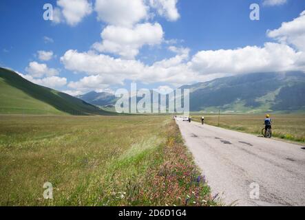 La route pavée qui traverse Pian Grande près de Castelluccio bondit de touristes sur les vélos, motos et voitures Banque D'Images