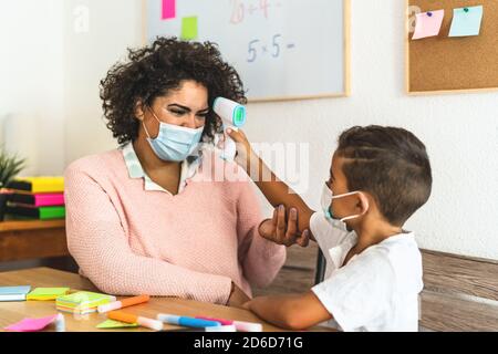 L'enfant contrôle la température sur l'enseignant dans la salle de classe pendant le virus corona Pandémie - concept médical et éducatif de soins de santé Banque D'Images