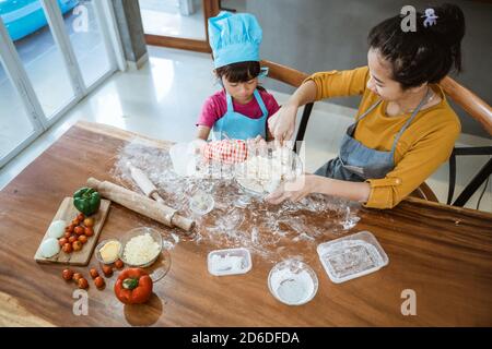 Mère et fille ayant plaisir à cuisiner ensemble et apprendre à faites une pizza tout en faisant cuire dans la cuisine à la maison Banque D'Images