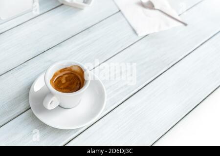 Tasse à café espresso noir italien chaude et savoureuse dans une tasse blanche sur une table en bois bleu clair vintage de style raerto au café ou au restaurant. Bonjour Banque D'Images