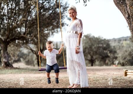 Femme enceinte s'amusant avec son fils tout-petit sur le faites un mouvement de stationnement Banque D'Images