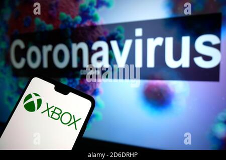 Le logo XBOX affiché sur un téléphone portable avec un modèle d'illustration du coronavirus affiché sur un moniteur en arrière-plan. Banque D'Images