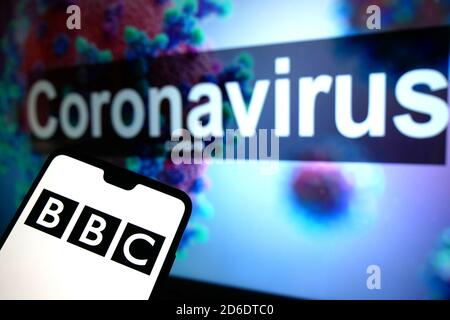 Le logo de la BBC affiché sur un téléphone portable avec un modèle d'illustration du coronavirus affiché sur un moniteur en arrière-plan. Banque D'Images