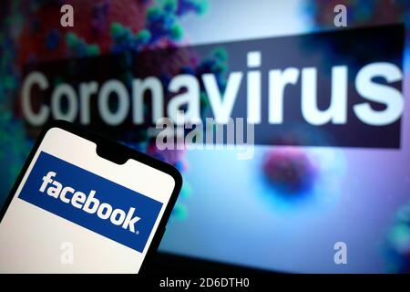 Le logo Facebook affiché sur un téléphone portable avec un modèle d'illustration du coronavirus affiché sur un moniteur en arrière-plan. Banque D'Images