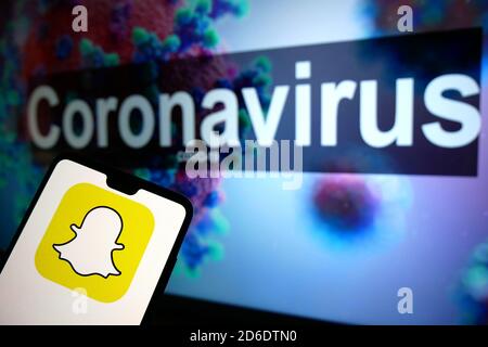 Le logo Snapchat affiché sur un téléphone mobile avec un modèle d'illustration du coronavirus affiché sur un moniteur en arrière-plan. Banque D'Images