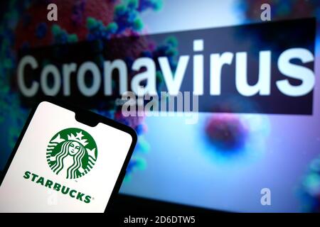 Le logo Starbucks affiché sur un téléphone portable avec un modèle d'illustration du coronavirus affiché sur un moniteur en arrière-plan. Banque D'Images