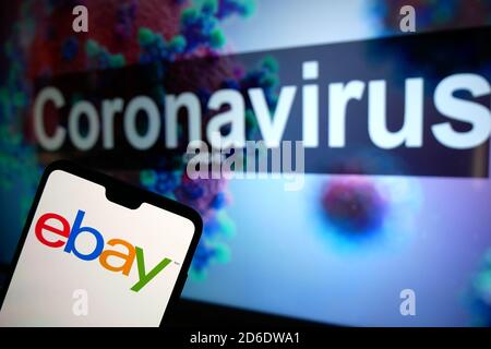 Le logo eBay affiché sur un téléphone portable avec un modèle d'illustration du coronavirus affiché sur un moniteur en arrière-plan. Banque D'Images