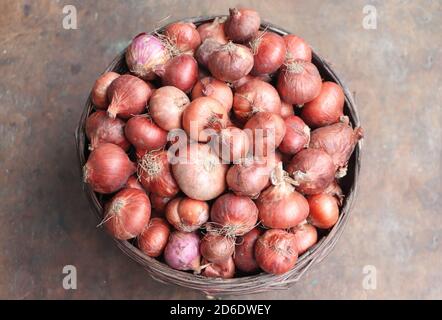 Vue de haut en bas des oignons conservés dans un panier sur la table en bois. Légumes pour une alimentation saine Banque D'Images