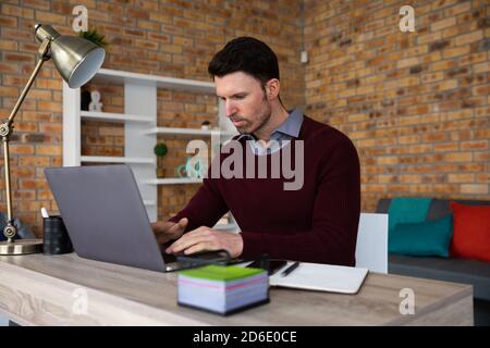 Homme utilisant un ordinateur portable assis sur son bureau Banque D'Images
