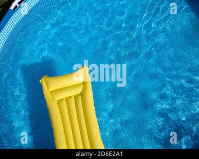 Vue de dessus d'un matelas gonflable jaune dans une ci-dessus piscine privée au rez-de-chaussée Banque D'Images