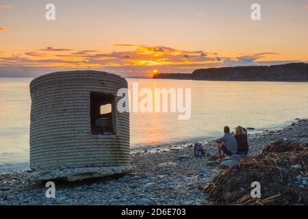 Kimmeridge Bay, Dorset, Royaume-Uni. 16 octobre 2020. Météo Royaume-Uni. Un couple assis sur la plage regardant le coucher du soleil à Kimmeridge Bay sur la Dorset Jurassic Coast. Crédit photo : Graham Hunt/Alamy Live News Banque D'Images