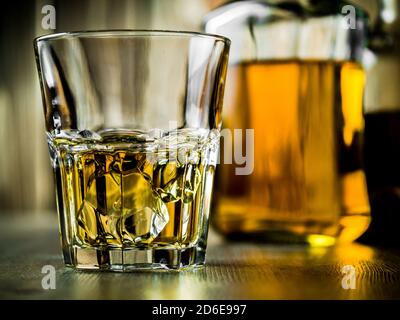 Verre de whisky sur les rochers et deux bouteilles sur un fond en bois Banque D'Images