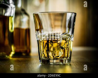 Verre de whisky sur les rochers et deux bouteilles sur un fond en bois Banque D'Images