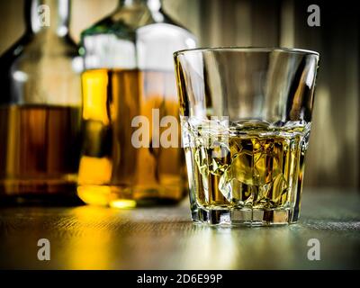 Verre de whisky sur les rochers et deux bouteilles sur un fond en bois Banque D'Images