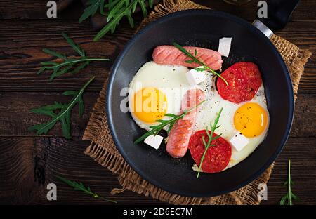 Petit-déjeuner anglais - oeufs frits, saucisses, tomates et feta. Cuisine américaine. Vue de dessus, au-dessus de la tête, espace de copie Banque D'Images