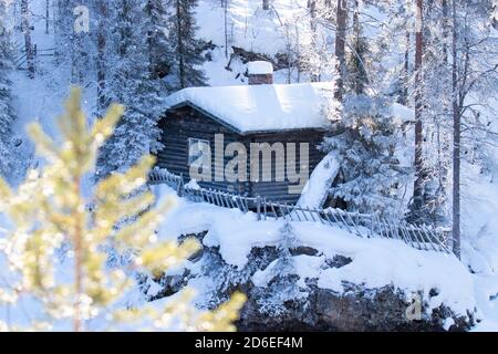 Une petite cabane d'hiver confortable au bord de la rivière dans la forêt finlandaise de taïga, en Europe du Nord. Banque D'Images