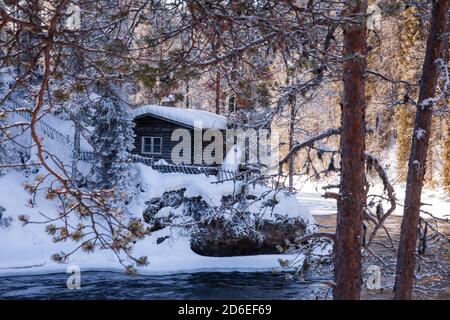 Une petite cabane d'hiver confortable au bord de la rivière dans la forêt finlandaise de taïga, en Europe du Nord. Banque D'Images