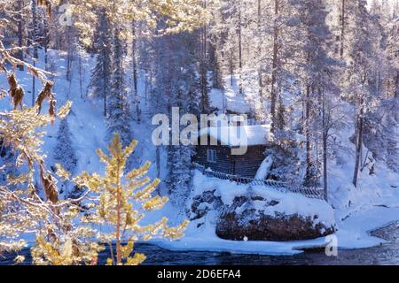 Une petite cabane d'hiver confortable au bord de la rivière dans la forêt finlandaise de taïga, en Europe du Nord. Banque D'Images