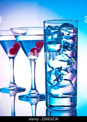 Deux verres de martini avec des cerises rouges et un verre de cocktail clair Banque D'Images