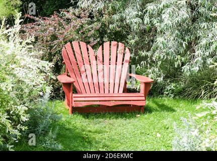 Chaise Adirondack en forme de coeur rouge dans le jardin Banque D'Images