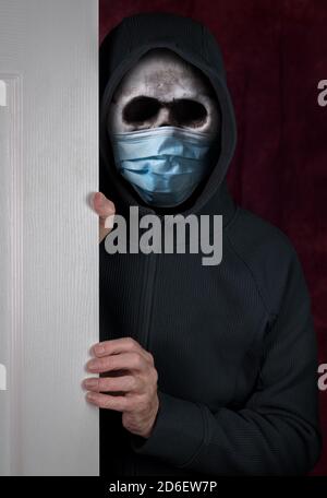 Stalker ou cambrioleur entrant dans une maison par la porte avec le port crâne humain équipé d'un masque médical contre le coronavirus pandémie Banque D'Images