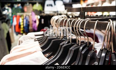 Gros plan des vêtements modernes et tendance pour femmes sont suspendus à des cintres en plastique noir dans un grand magasin de vêtements. Achats en ligne pour un caillot décontracté Banque D'Images