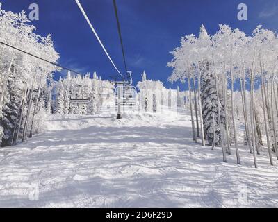 Un télésiège de ski vide, sans arbres couverts dans le paysage d'hiver, contre un ciel bleu vif. Station de ski du Colorado. Personne. Copier l'espace. Banque D'Images