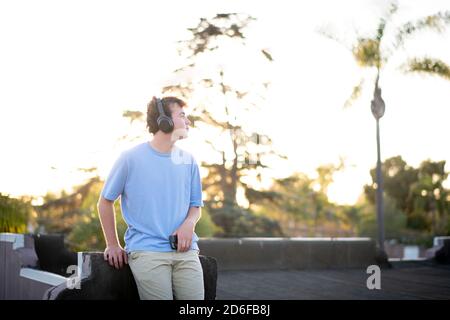 un adolescent sur le toit écoute de la musique sur son réseau sans fil casque Banque D'Images